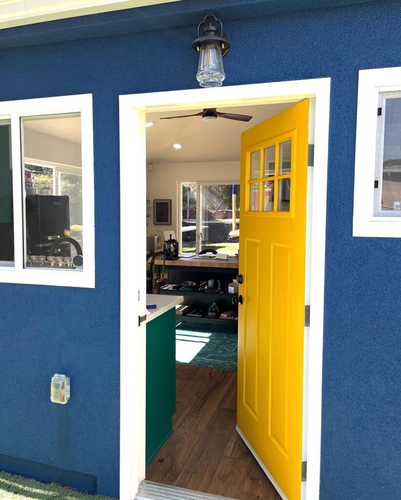 yellow door in blue wall opening to studio interior