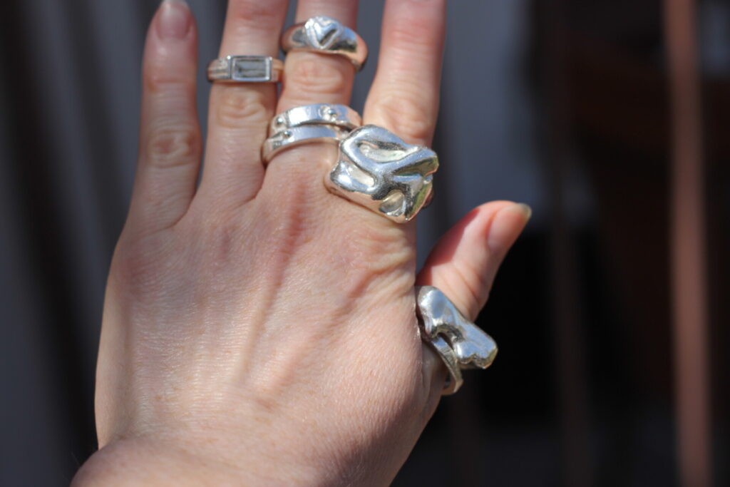 hand with multiple wax cast rings on different fingers